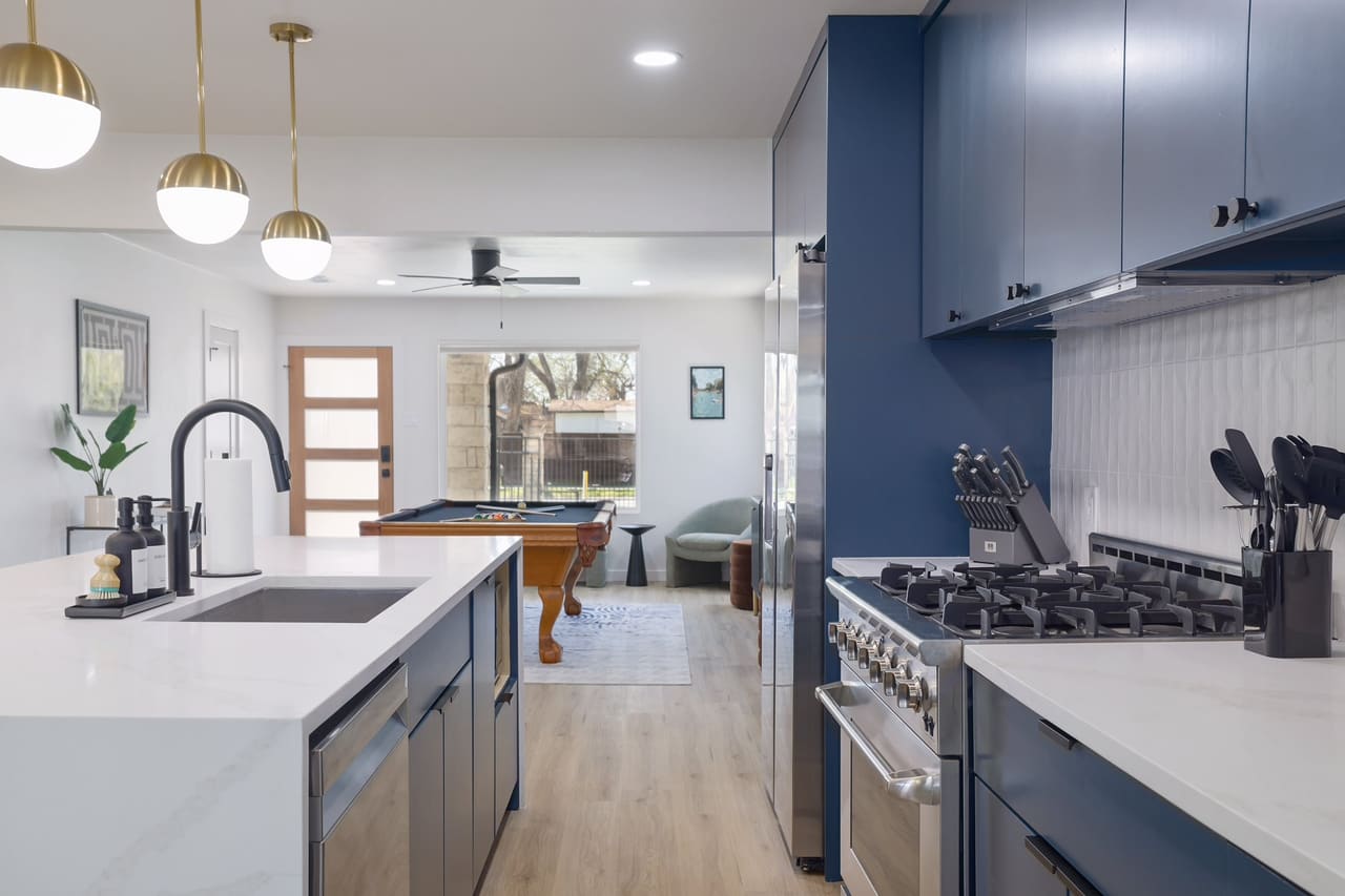 Austin East Bird kitchen with navy cabinets, quartz island, and brass pendants
