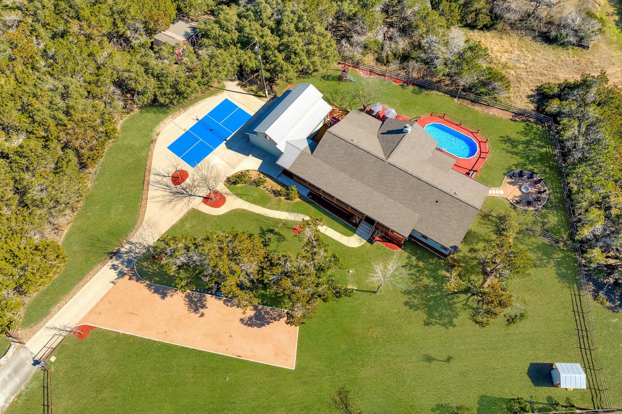 Fitzhugh Lodge aerial view with private pool, sport court, and wooded acreage